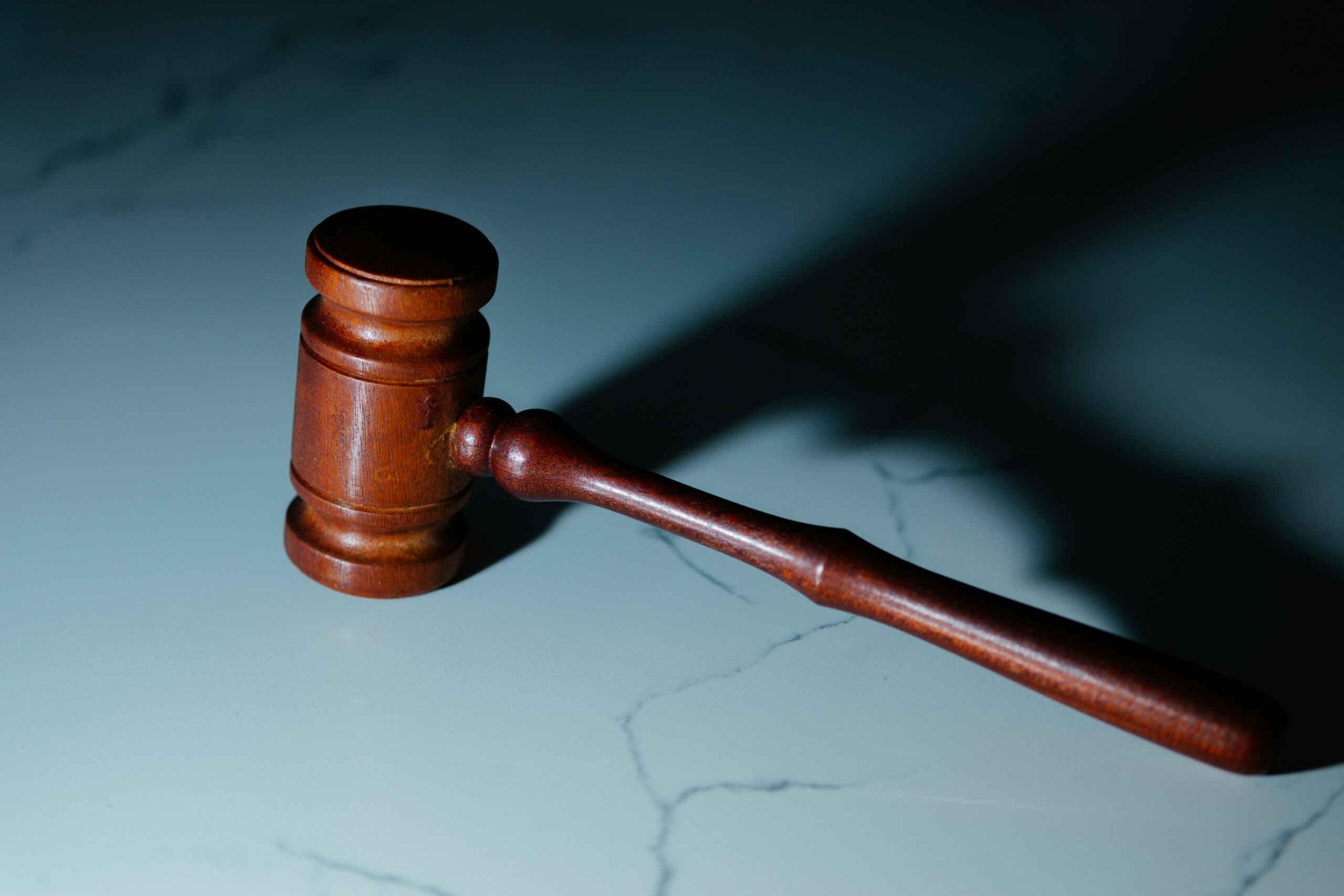 A wooden gavel rests on a marble tabletop.
